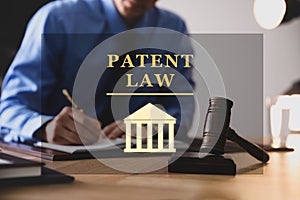 Male lawyer working at table in office, focus on gavel. Patent Law