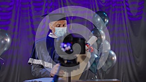 male lecturer wearing medical mask observes precautions and solemnly delivers diplomas online via video link to