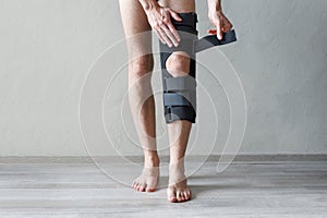 Male leg wearing knee brace on gray background. Orthopedic Anatomic Orthosis. Braces for knee fixation, injuries and pain. Foot