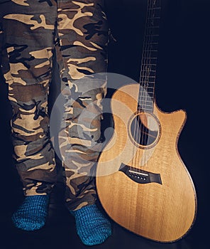 Male legs with blue woolen socks beside acoustic guitar