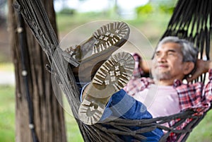 a male legs in boots on rope hammock background nature