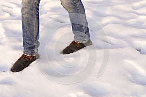Male legs in brown boots and blue jeans are going on the snow. Copy space. Wirst step after snow catastrophe.