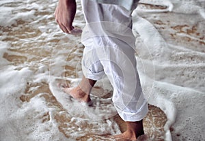 Male legs in coastal ocean foam