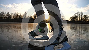 Male legs in figure skates sliding on lake covered by ice. Man enjoying sport in cold weather with sunlight reflected in