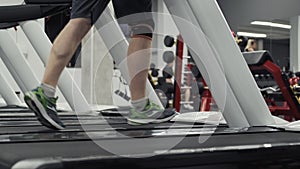 Male legs running on treadmill in gym. Close up of feet running on treadmills