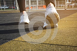 male legs shod in white sneakers on the playground