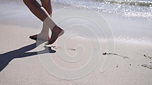 Male legs walking along sea coastline. Man spending summer holiday at seaside leaving footprints at wet sand beach