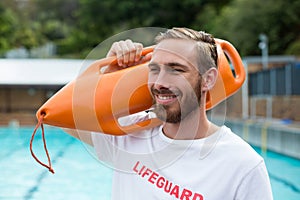 Male lifeguard carrying rescue can at poolside