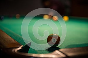 Male lines up billiard shot to sink a ball by the corner pocket