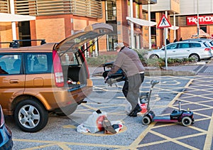 Male loading a diabled persons mobility scooter into the back of