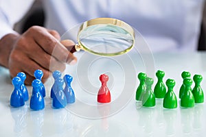 Male Looking At Colorful Pawns With Magnifying Glass