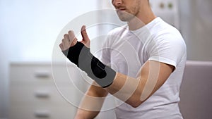 Male looking at hand with titan wrist support, orthopedic equipment, trauma