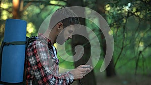 Male lost in forest using compass to navigate, finding way out from woods