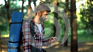 Male lost in forest using compass to navigate, finding way out from woods photo