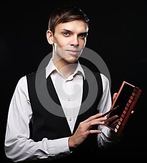 Male make-up artist staying on dark background, holding profes