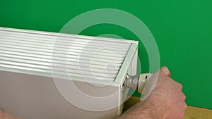 Male man arms increase radiator temperature and warm hands on it.