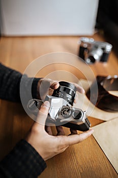 Male man hands adjusts the lens pentax retro camera on a white table