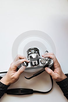 Male man hands holds film in pentax retro camera on a white table