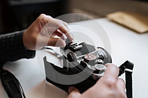 Male man hands reloading film in pentax retro camera on a white table