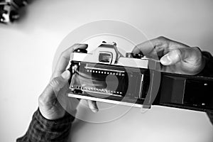 Male man hands reloads film in pentax retro camera on a white table