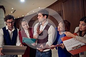 A male manager having a briefing with his team at the hotel hallway. Hotel, business, people