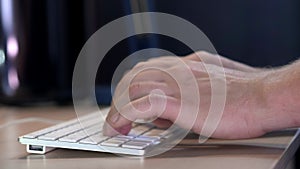 Male manager typing on the keyboard in the office in the evening. A smart watch is worn on the hand. Close-up.