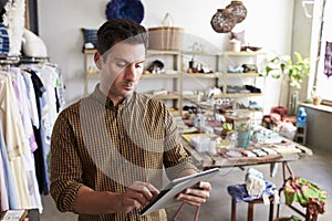 Male manager using tablet computer in clothes shop