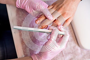 Male manicure. Professional master in gloves makes a manicure on male hands with the help of a professional tool.