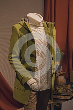 Male mannequin in a sweater and coat in a shop window. Clothing