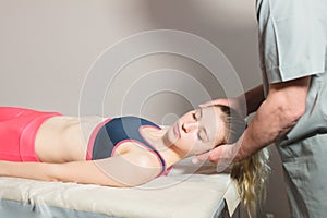 Male manual visceral therapist masseur treats a young female patient. Warm up the shoulders and neck