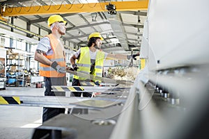 Male manual workers manufacturing sheet metal at industry