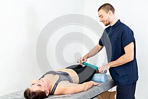 A male massage therapist in a blue suit makes a sports massage to a woman.