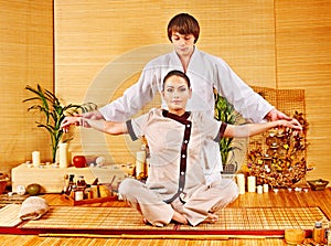 Male masseur doing massage woman in bamboo spa.