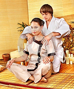 Male masseur doing massage woman in bamboo spa.