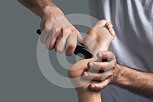 Male masseur hands doing reflexology massage on female foot reflex zones in the spa salon.