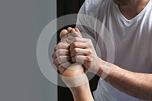 Male masseur hands doing reflexology massage on female foot reflex zones in the spa salon.