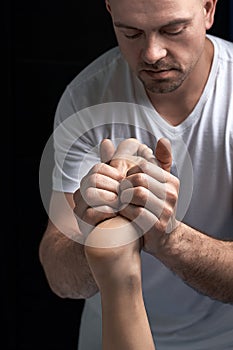 Male masseur hands doing reflexology massage on female foot reflex zones in the spa salon.