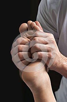 Male masseur hands doing reflexology massage on female foot reflex zones in the spa salon.