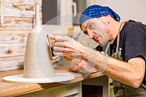 Male master potter in studio finishing detail works on new bawl