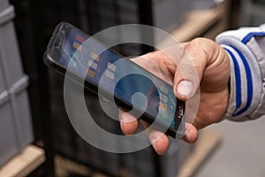 A male master worker in his hand holds a cellphone on which glass is cracked. It is located in an artisan and construction