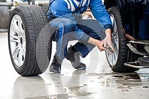 Male Mechanic Changing Car Tire In Garage