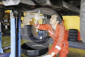 Male mechanic engineering working under Vehicle in Car Service