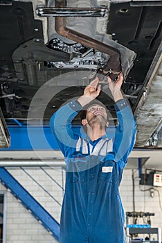 Male Mechanic Examining Exhaust System Of Car