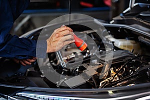 Male mechanic holding and shining flashlight to checking car engine problem