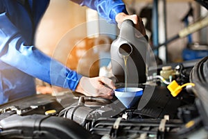 Male mechanic refilling car oil in service center