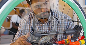 Male mechanic repair customer bicycle wheel in workshop