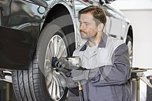 Male mechanic repairing car's wheel in workshop