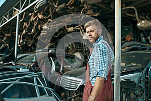 Male mechanic at the stack of cars on junkyard