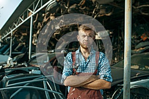 Male mechanic at the stack of cars on junkyard