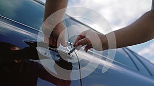 Male mechanic or thief holding lockpicker to open car door. Close up